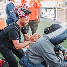 woman giving another women a back message on a massage chair at public event