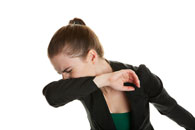 woman sneezing into arm
