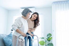 asian daughter supports grandmother using walker
