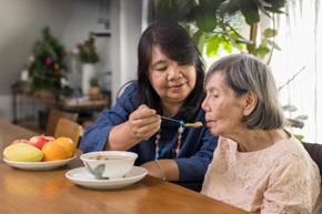 daughter feeding soup to elderly mother