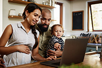 mom, dad, and baby looking at laptop screen