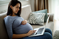 pregnant woman looking at laptop